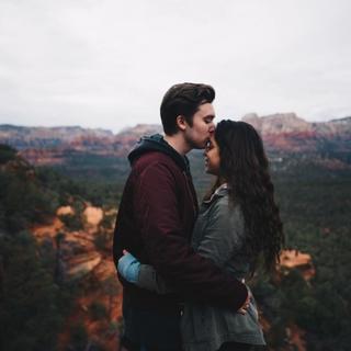 Photo by Nathan McBride on Unsplash. Picturing a couple holding around each other with a mountain view in the background.