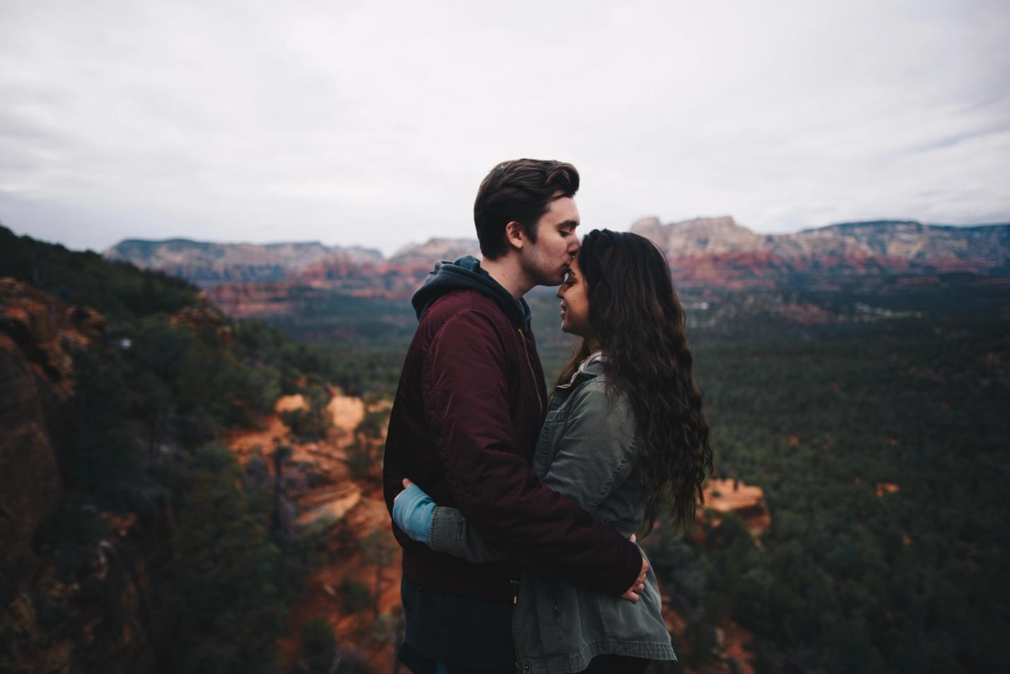 Photo by Nathan McBride on Unsplash. Picturing a couple holding around each other with a mountain view in the background.