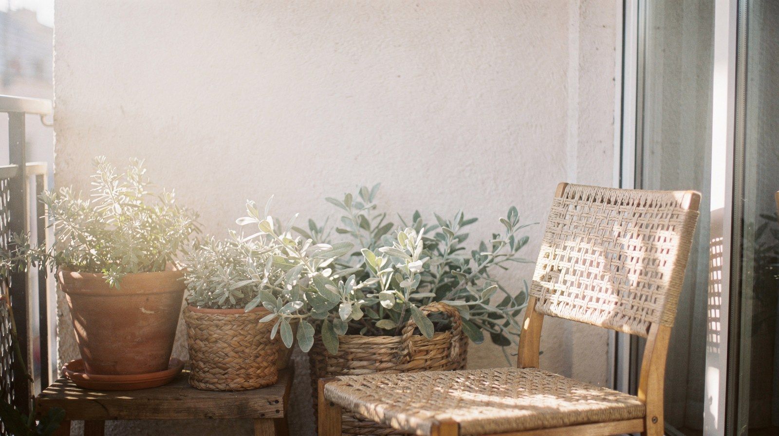 La luce del sole attraversa un balcone con piante e una sedia, in una giornata d’inverno.