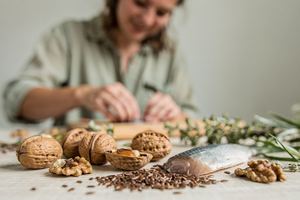 Noci, semi di lino e un trancio di pesce fresco su un piano di legno chiaro.