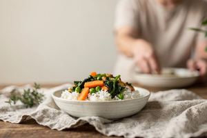 Una ciotola di riso con verdure cotte su un telo di lino.