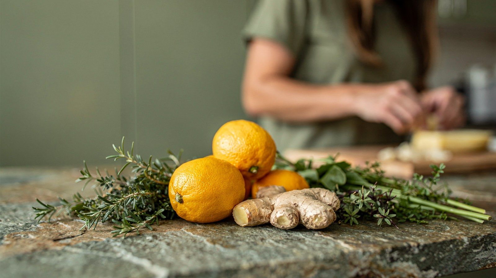 Agrumi, zenzero ed erbe fresche sul piano di una cucina.