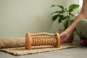 Un rullo di legno per i piedi e un tappetino arrotolato accanto a una pianta.