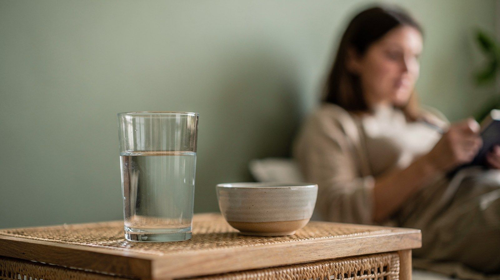Un bicchiere d’acqua e una piccola ciotola di ceramica sul comodino.