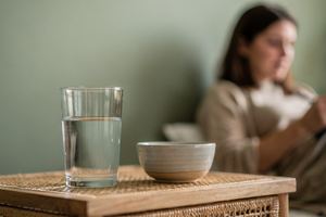Un bicchiere d’acqua e una piccola ciotola di ceramica sul comodino.