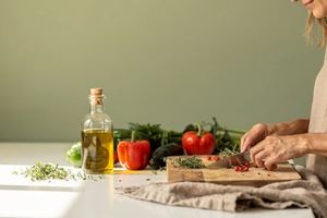 Il piano di una cucina luminosa con verdure, olio ed erbe pronti da usare.