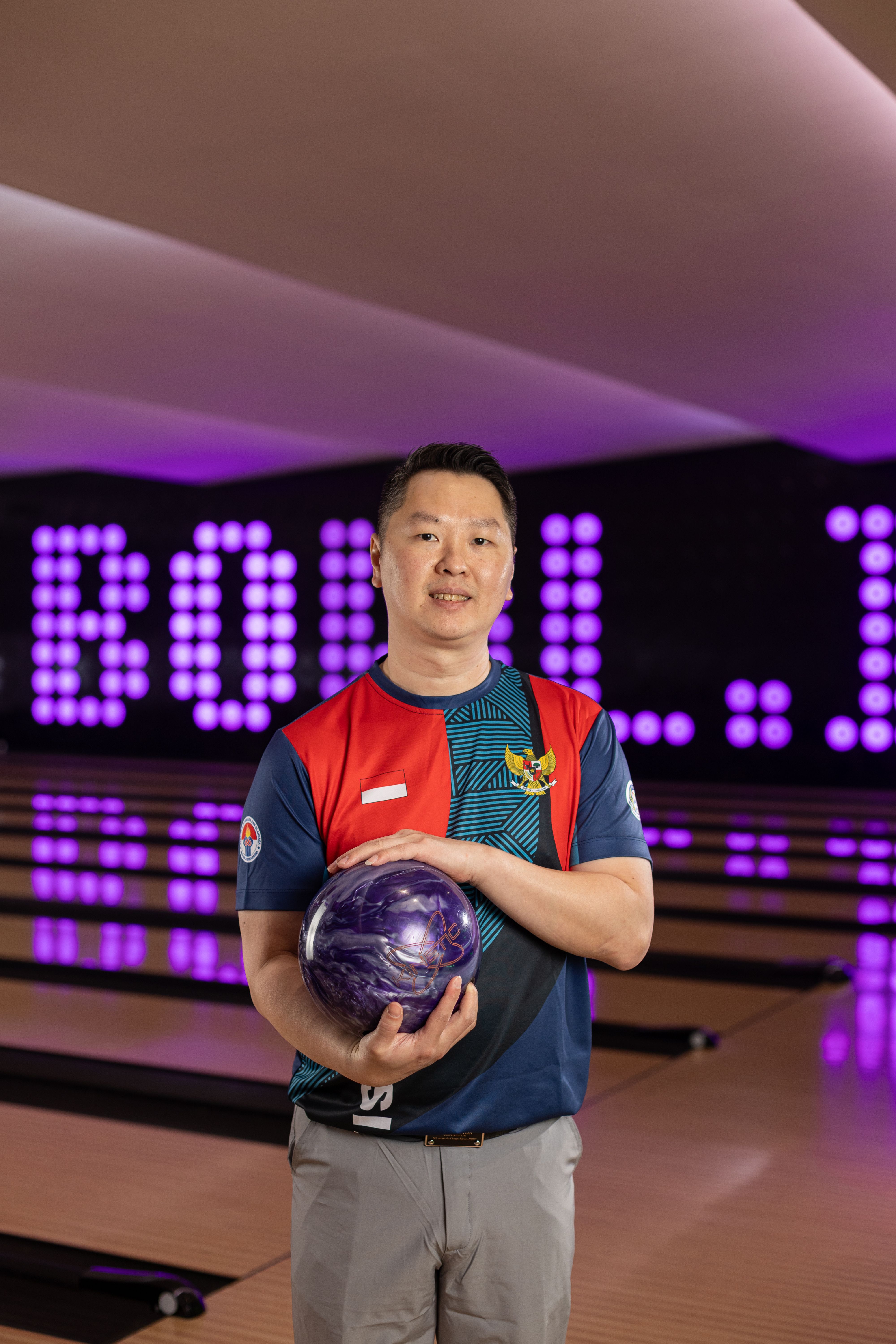 Coach William memegang bola boling di depan lajur Bowl.inc