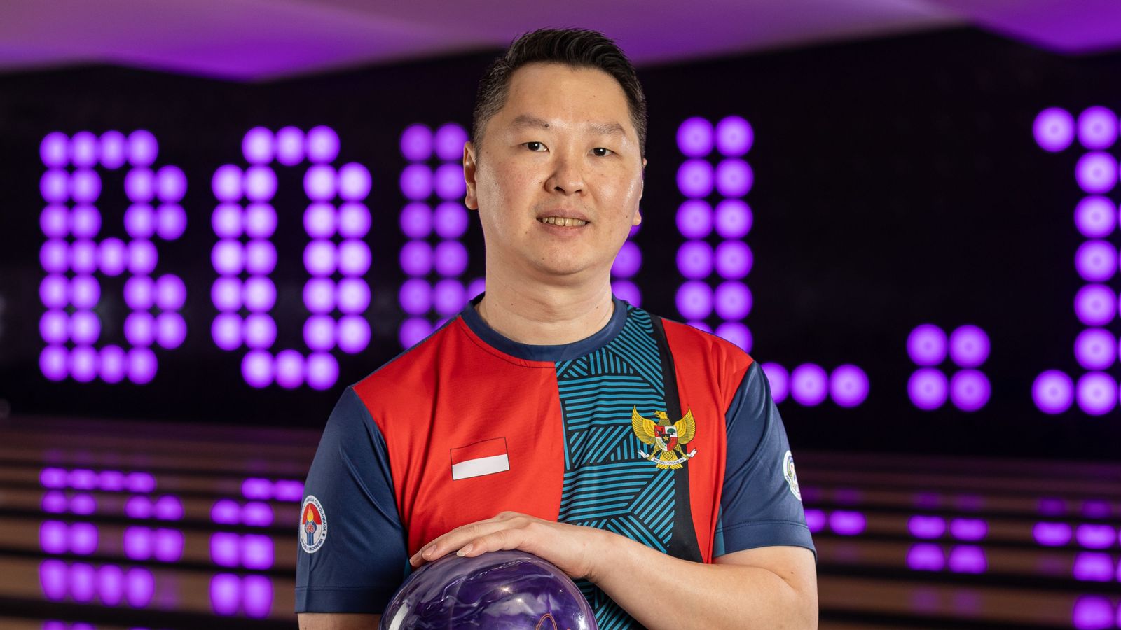 Coach William memegang bola boling di depan lajur Bowl.inc
