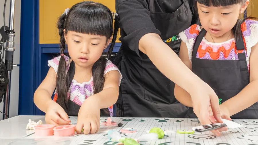 Dua anak mengikuti arahan chef di meja kerja Cook.inc