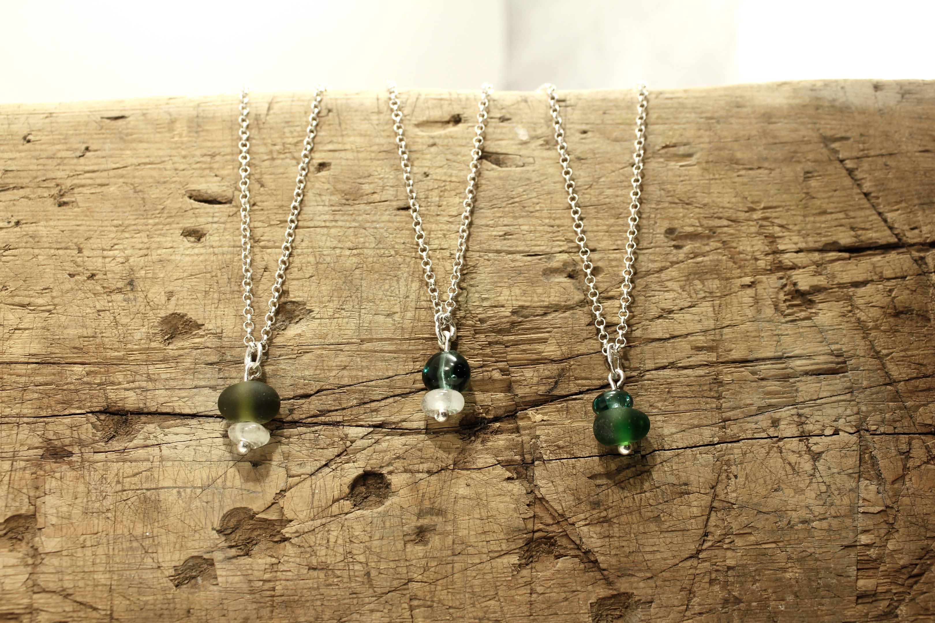 Three necklaces placed on top of a wood slab