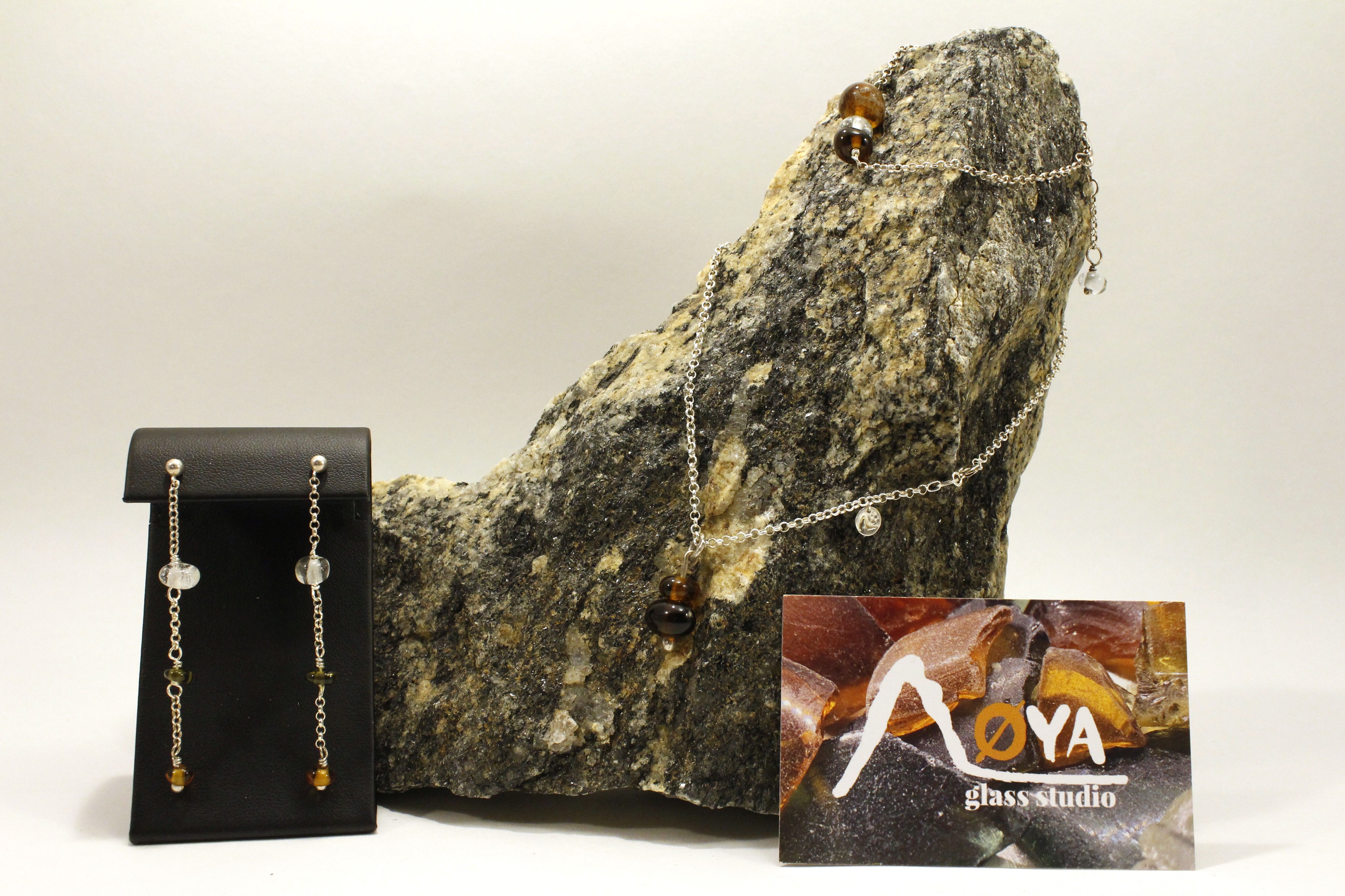 Glass jewelry on a rock with Øya Glass Studio logo