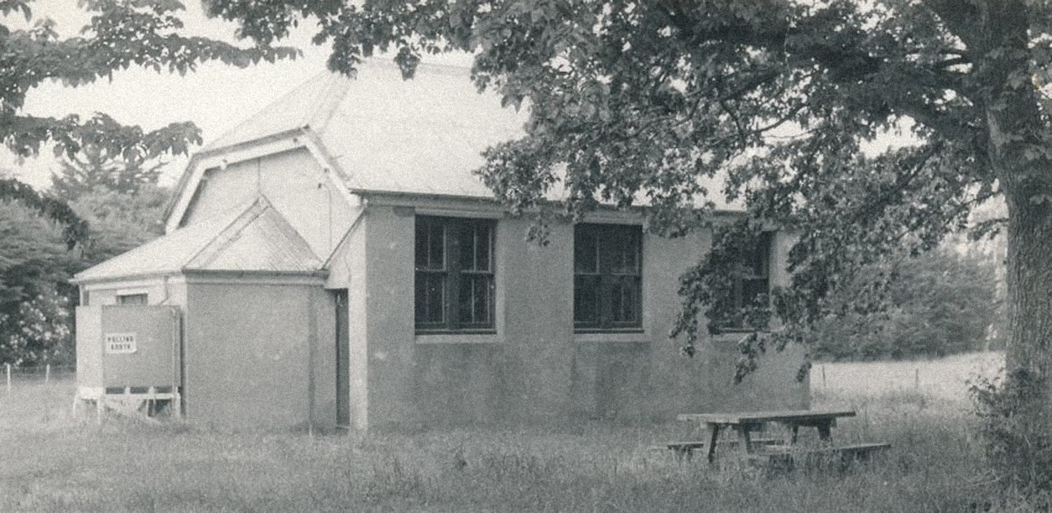 Black-and-white photograph of the Barrhill School building, a single-storey weatherboard building beneath large trees.