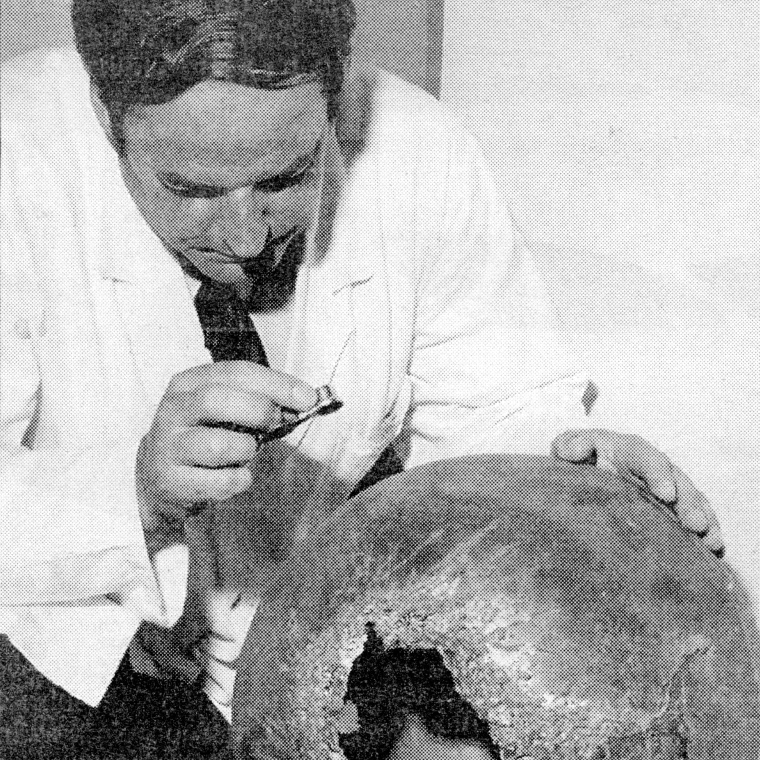 Black-and-white photograph of a DSIR scientist in a white coat examining the burnt-out hole in the first space ball.