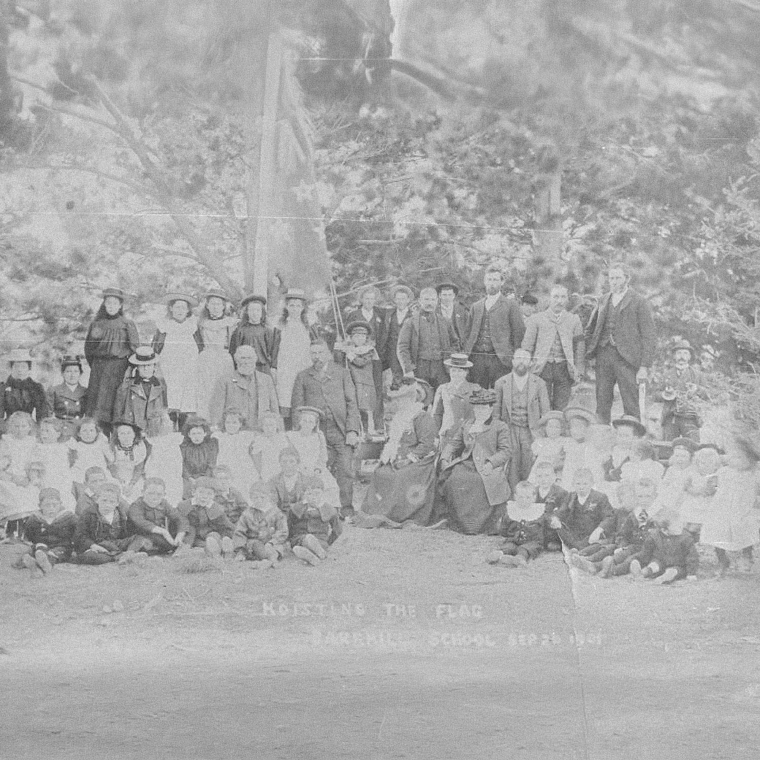 Black-and-white photograph of a large group of parents and schoolchildren posed in rows outside Barrhill School for a flag-hoisting ceremony in 1901.