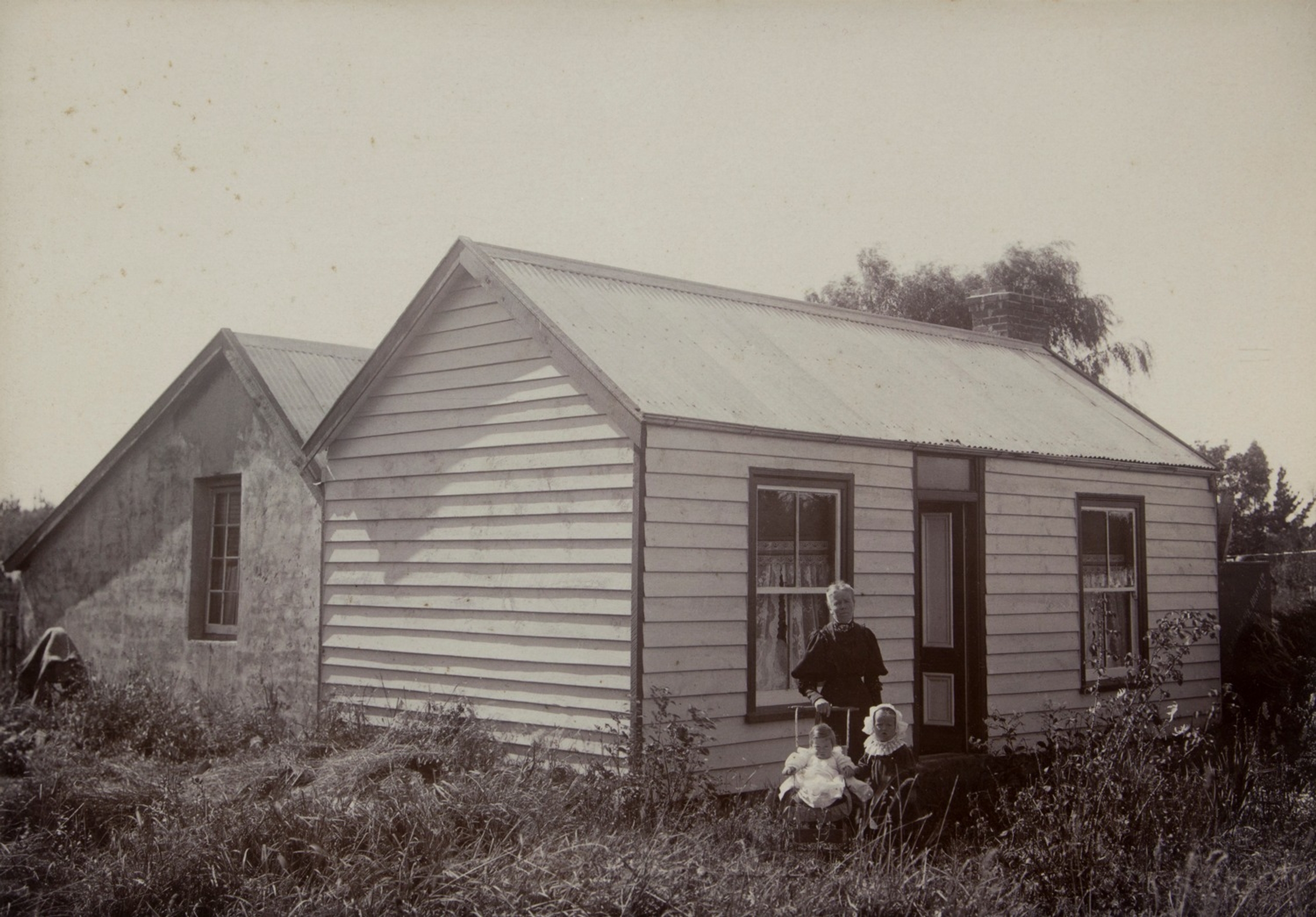 Early photograph of the Barrhill Hotel, a single-storey weatherboard building with gabled roofs, with a figure standing outside.
