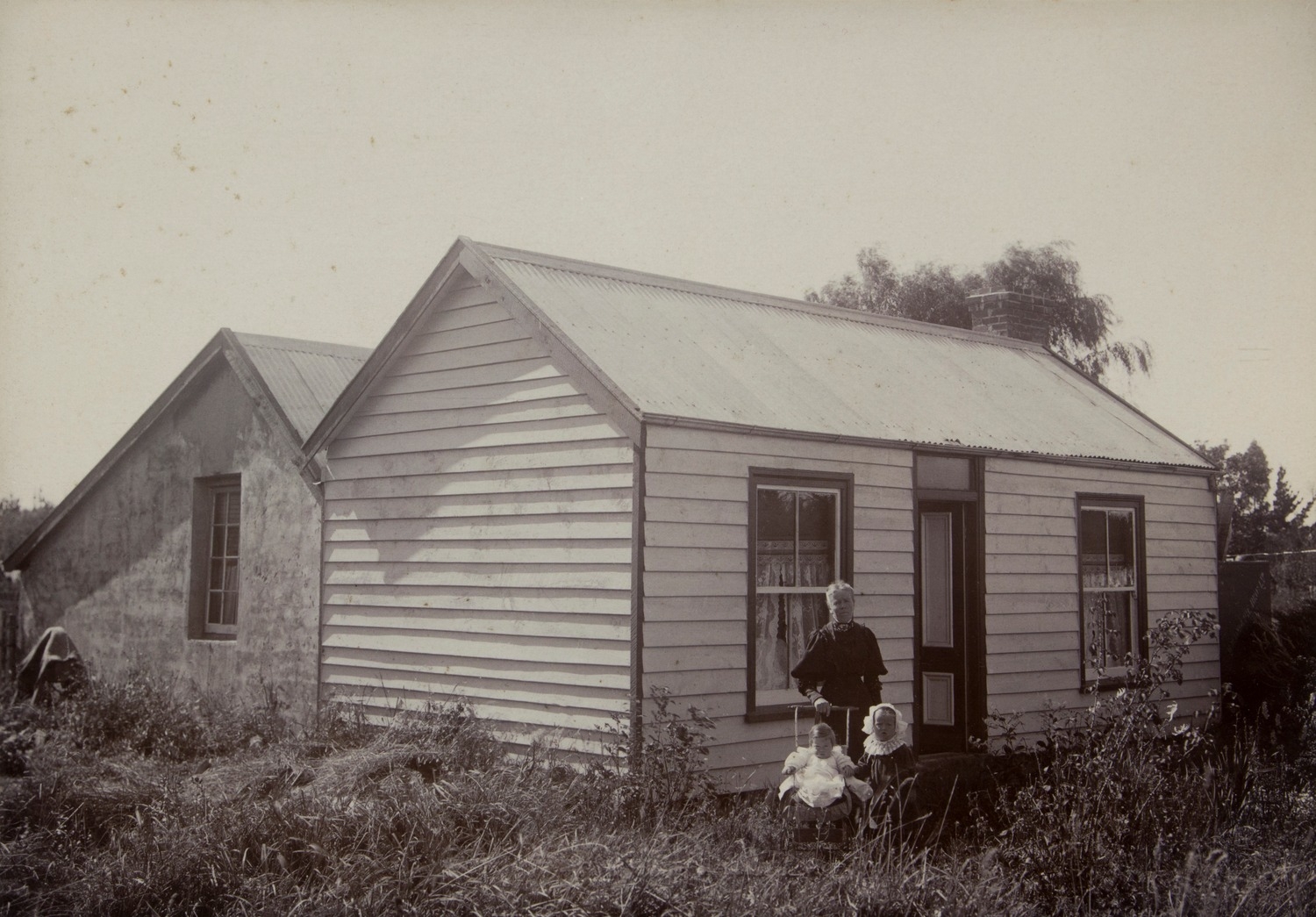 Early photograph of the Barrhill Hotel, a single-storey weatherboard building with gabled roofs, with a figure standing outside.