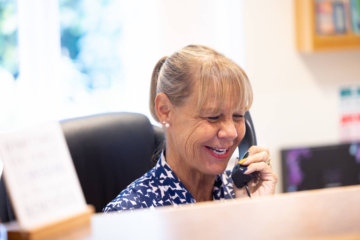 A receptionist at Ashbury Dental Care smiling while talking on the phone