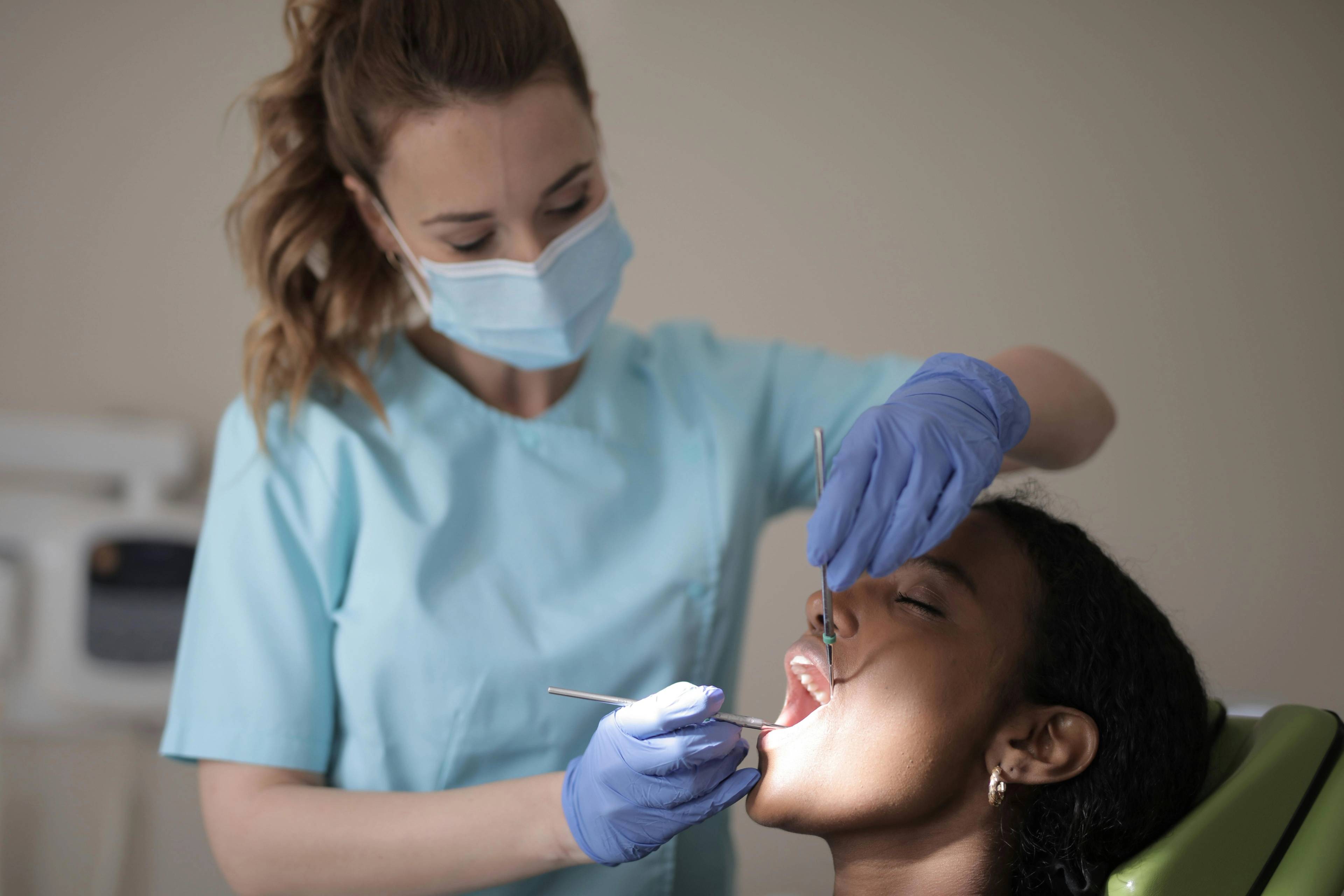 A masked dentist gives a patient a dental check up