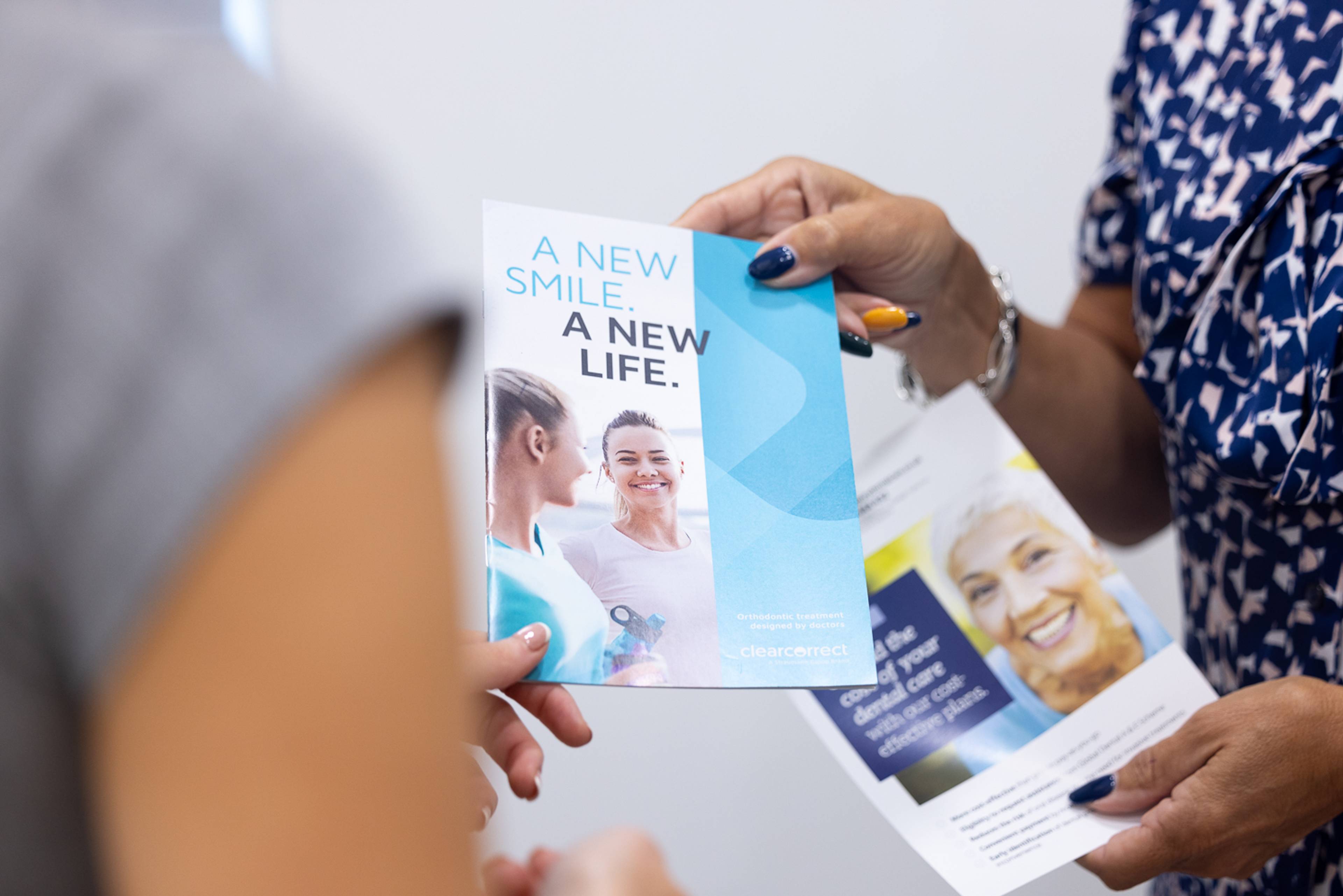 A patient is handed a leaflet about dental plans