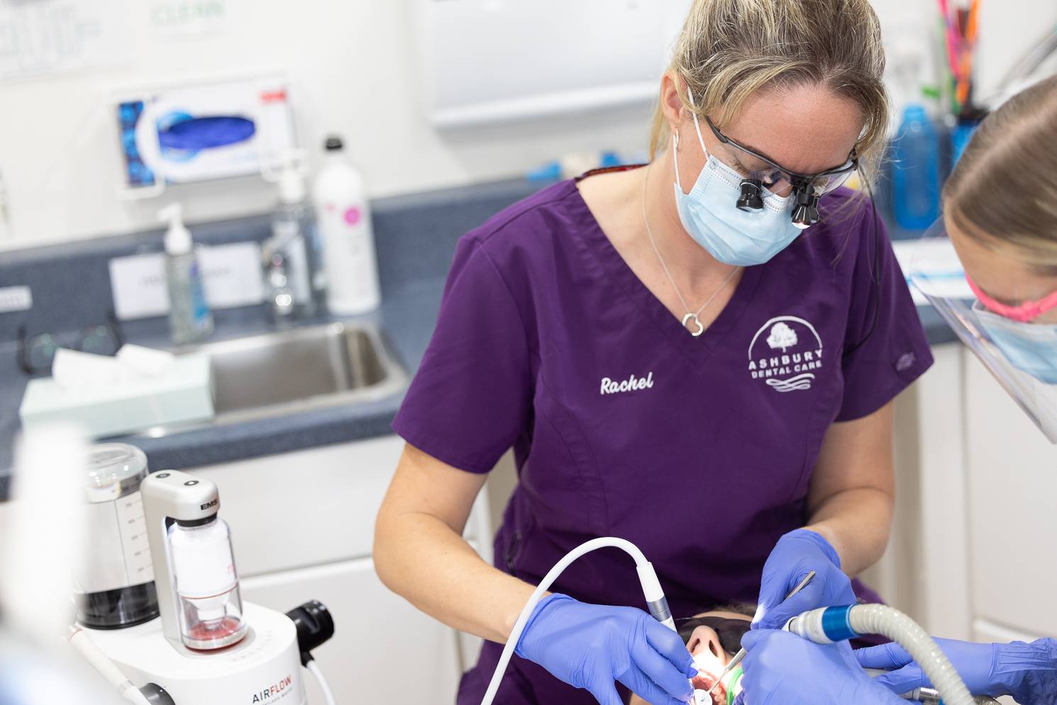 A masked dentist at Ashbury Dental Care gives a patient a treatment