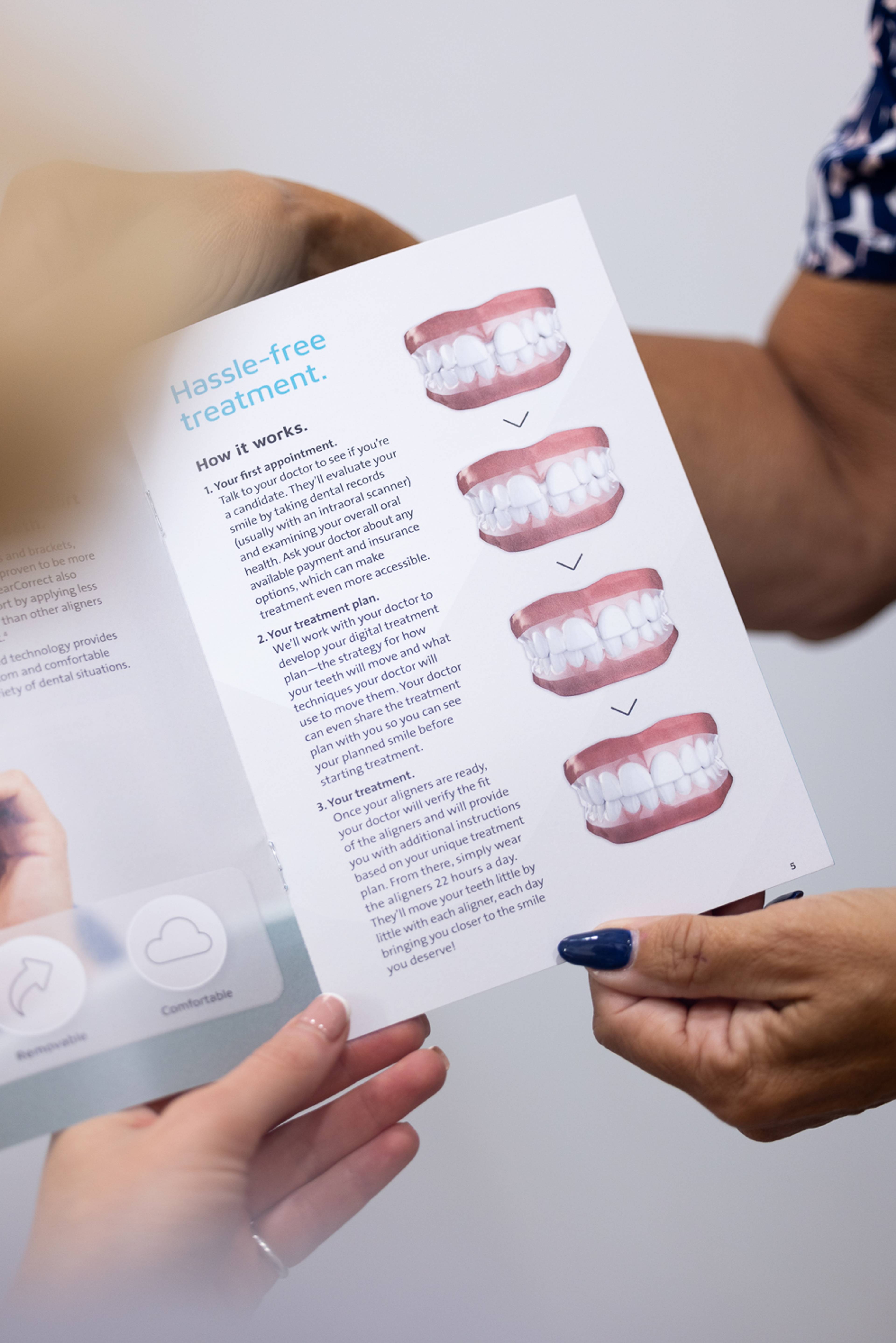 Patient looking at a leaflet about clear aligners showing an illustration of how the aligners straighten teeth over time