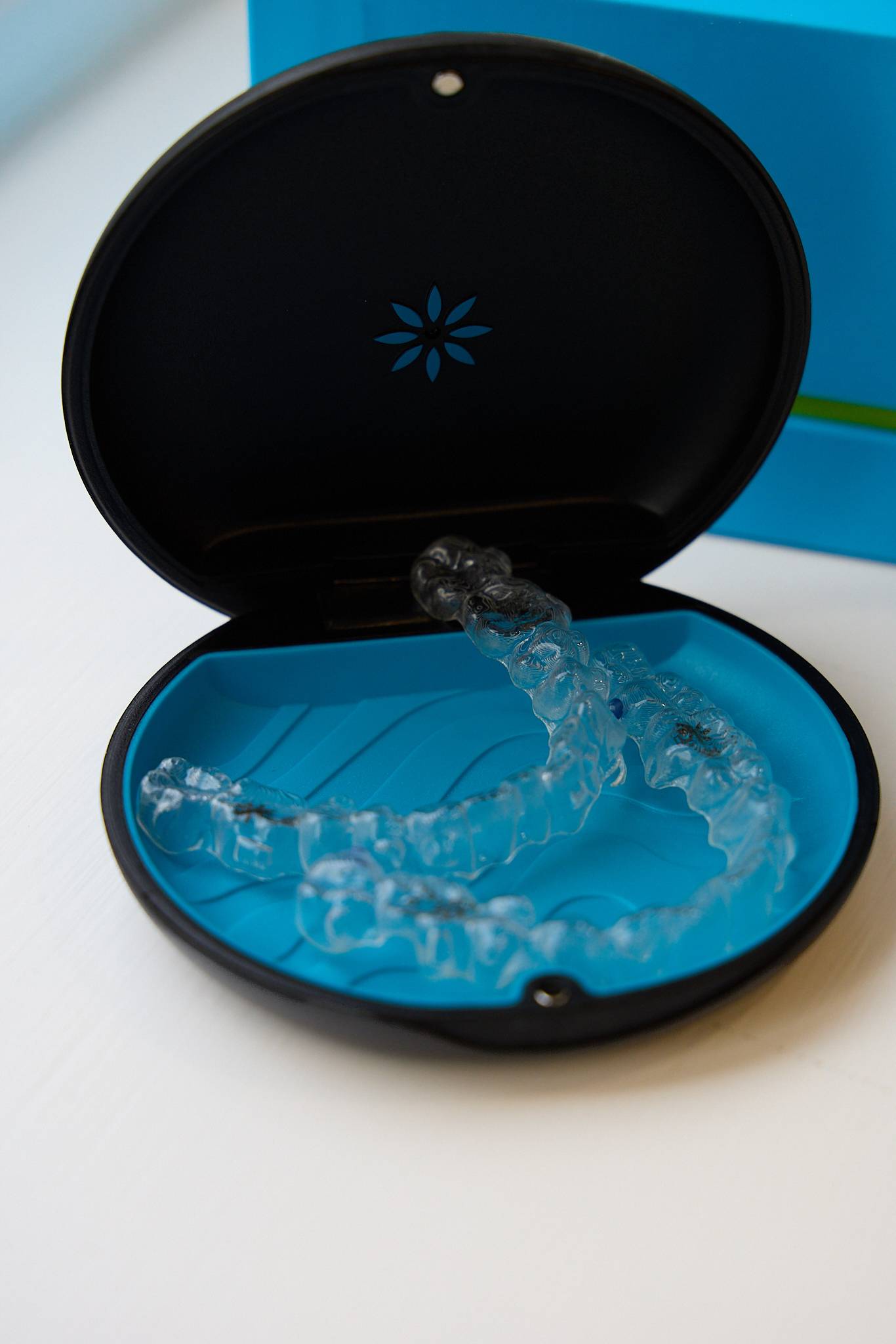 Clear dental aligners displayed inside an open black and blue protective case
