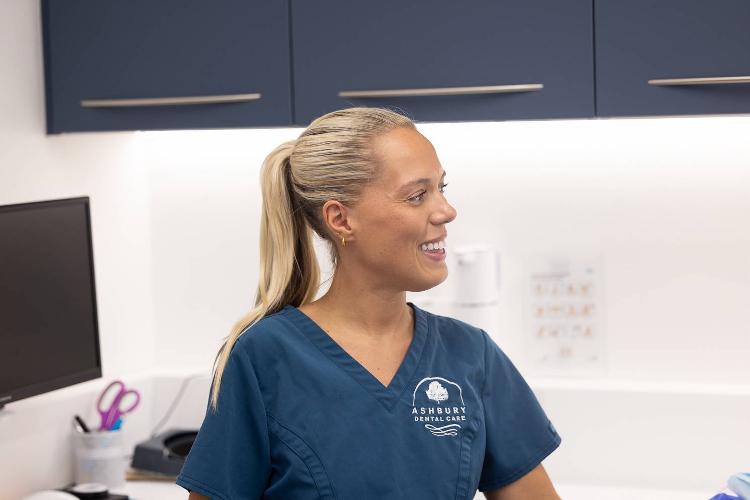 A dentist wearing smiling in a treatment room