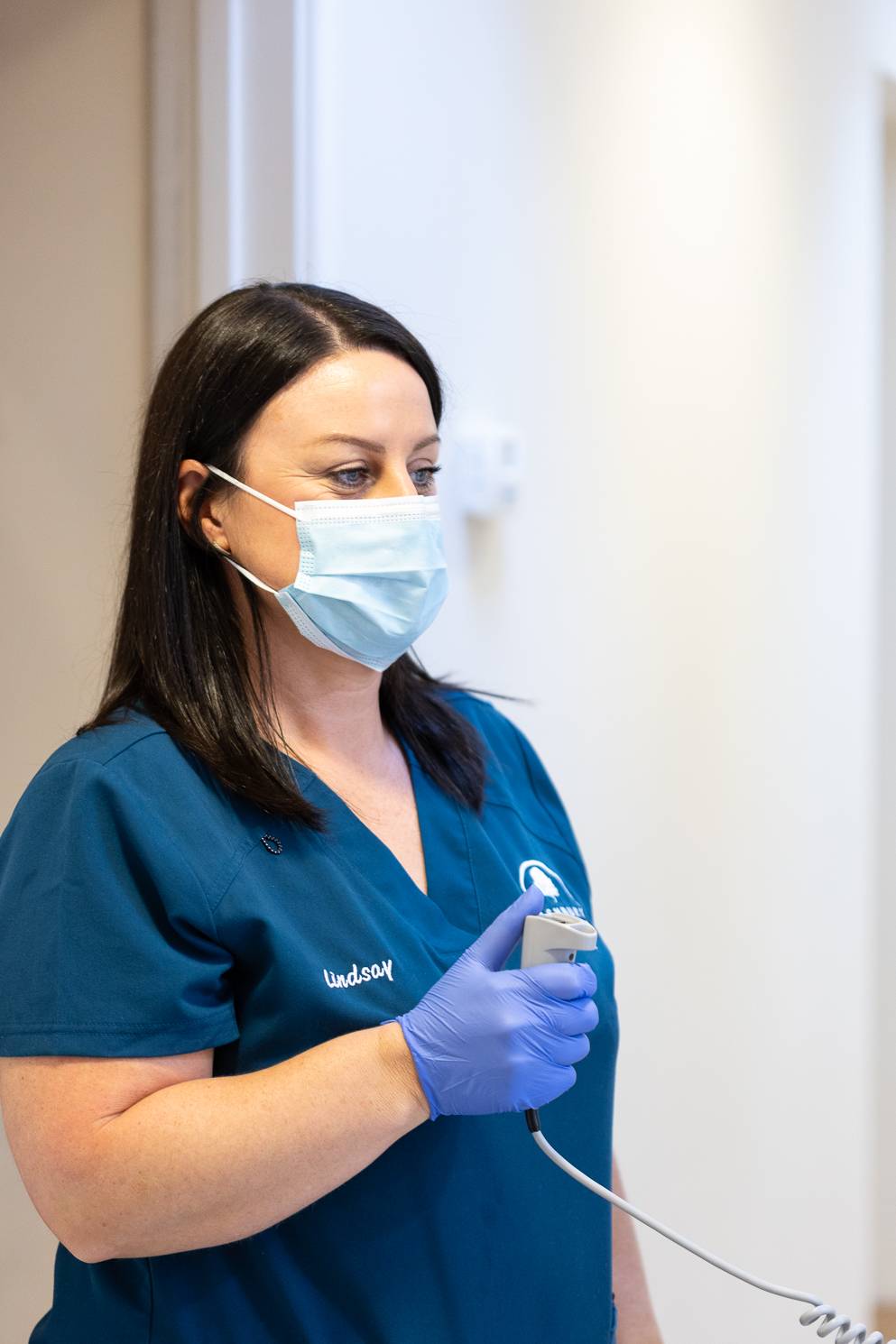 A dentist wearing a face mask taking an xray of a patient who is not in the picture