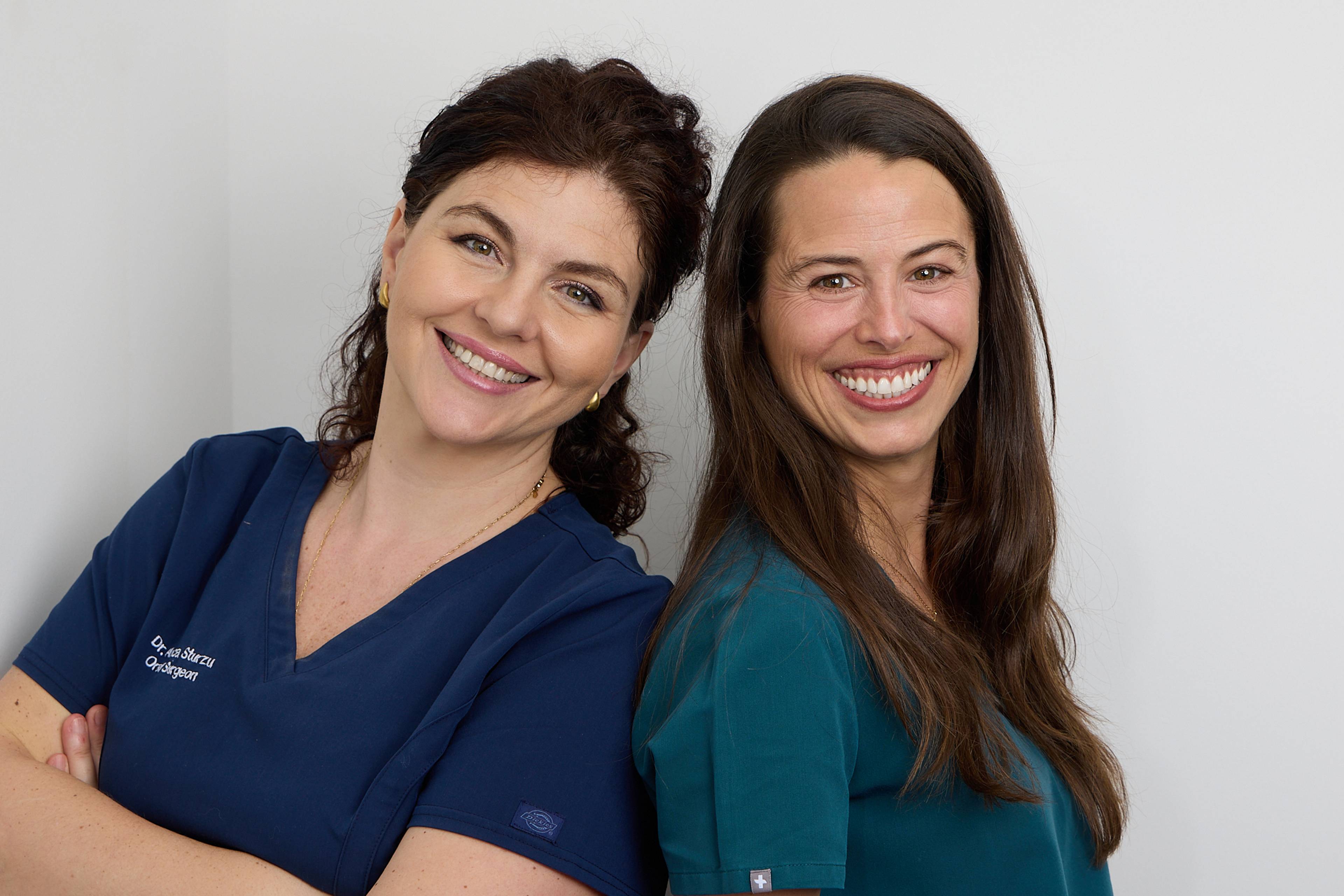 Dentists stood back to back smiling at Ashbury Dental Care