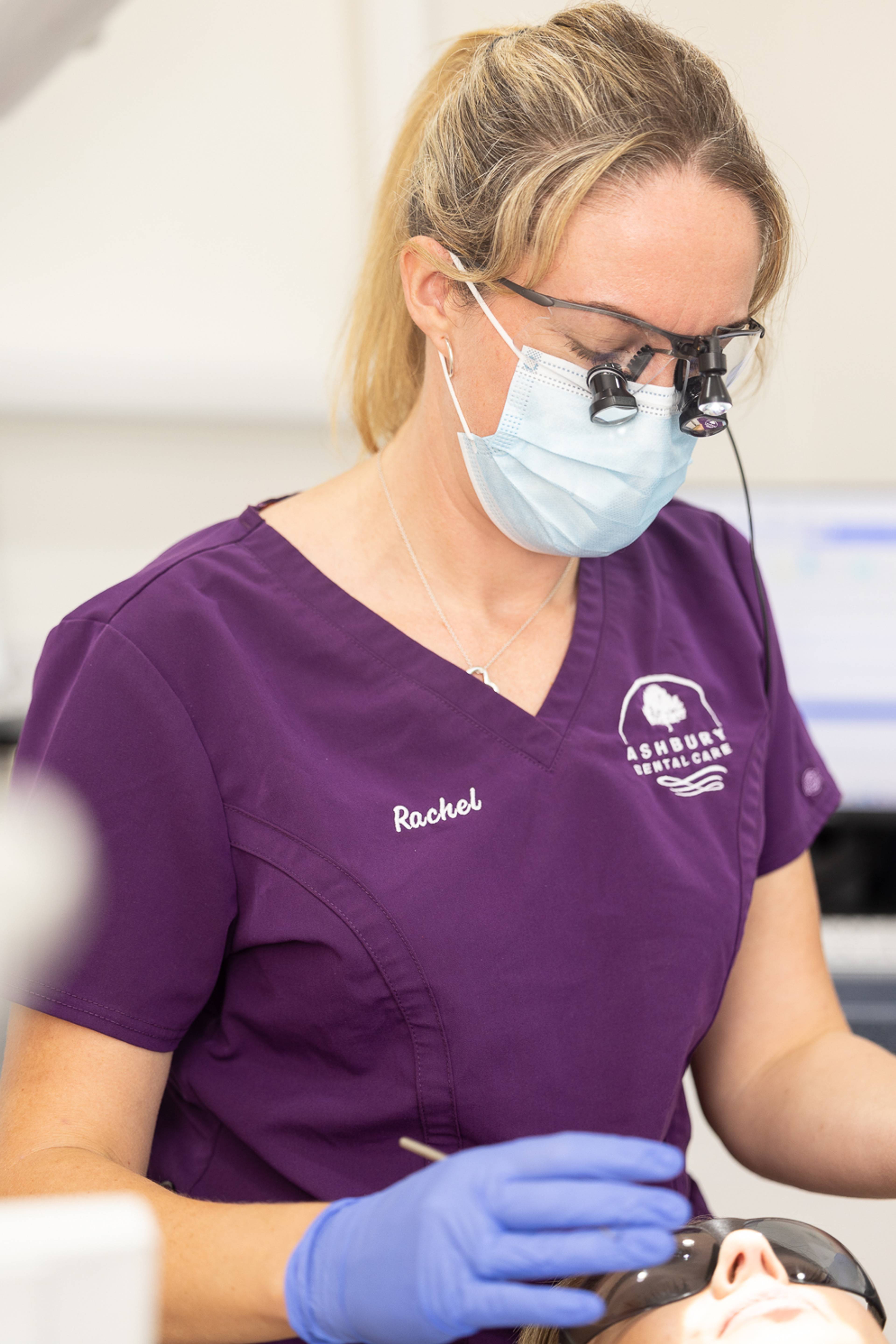 A dentist looking at a patient through loupes