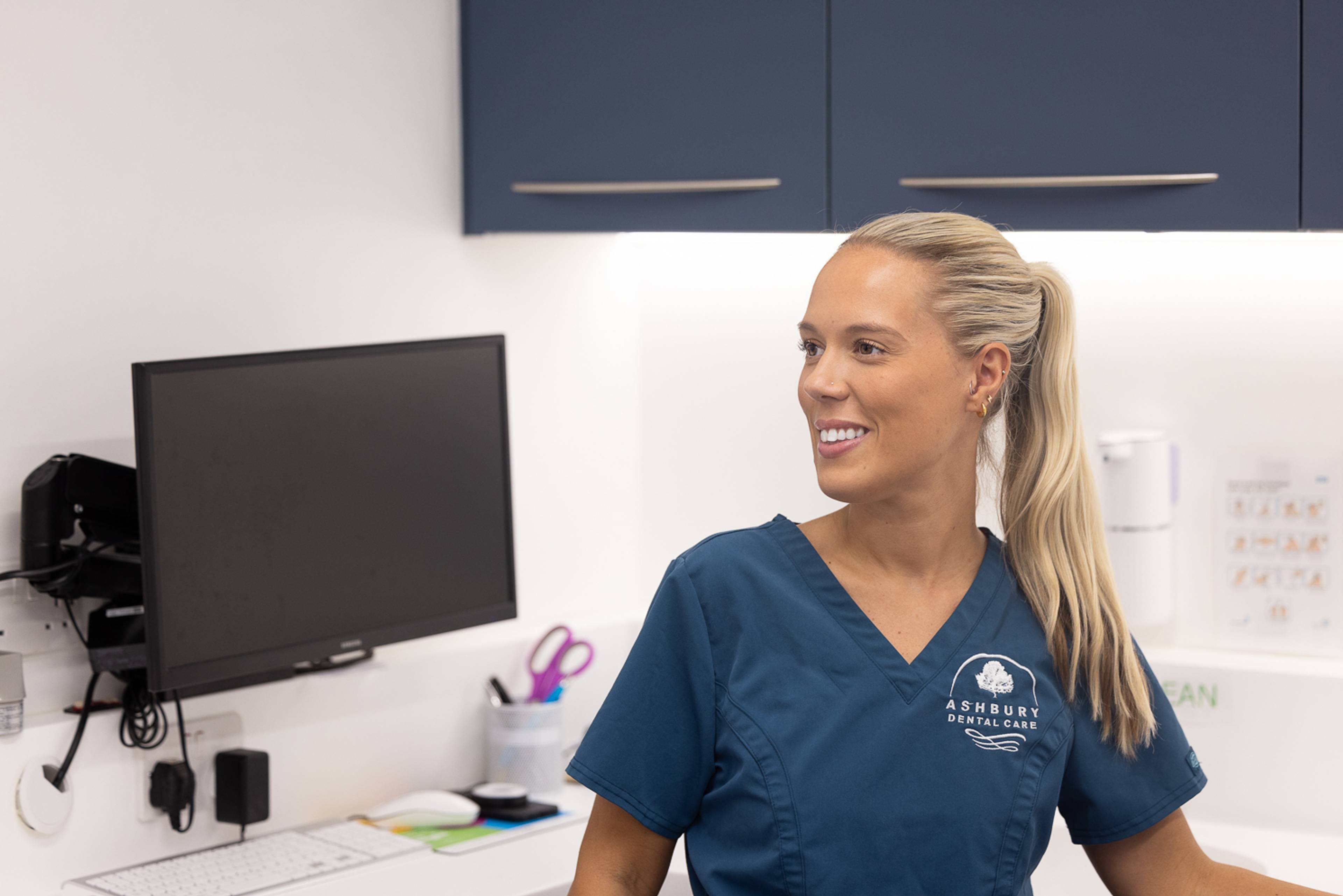 A dentist smiling in a treatment room