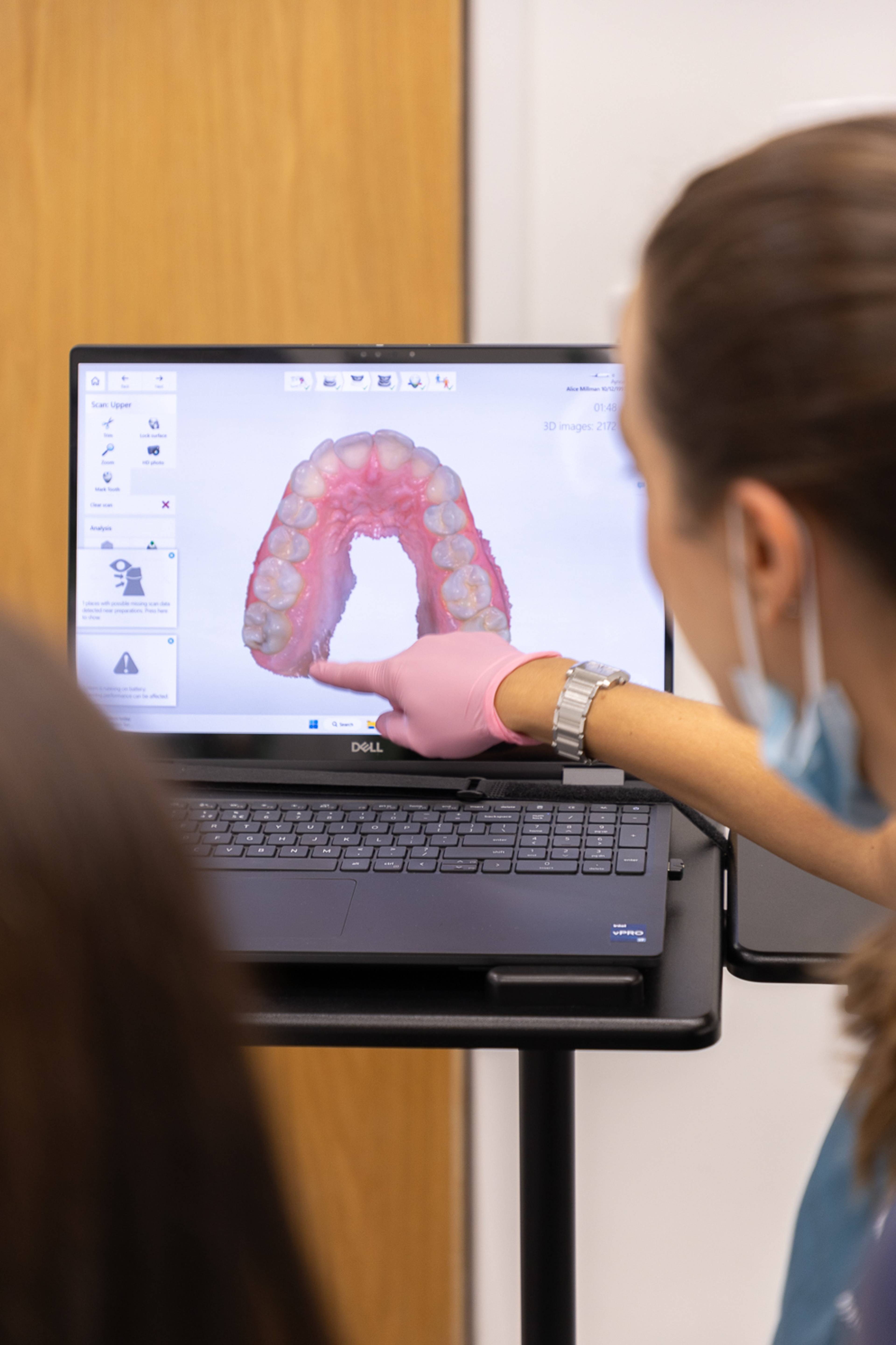 A dentist looks at a scan of a patient's teeth