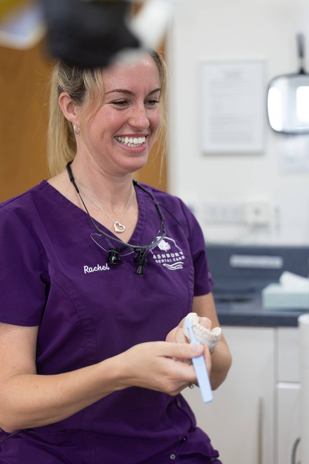 A dentist at Ashbury Dental Care demonstrates proper brushing technique on a model of teeth