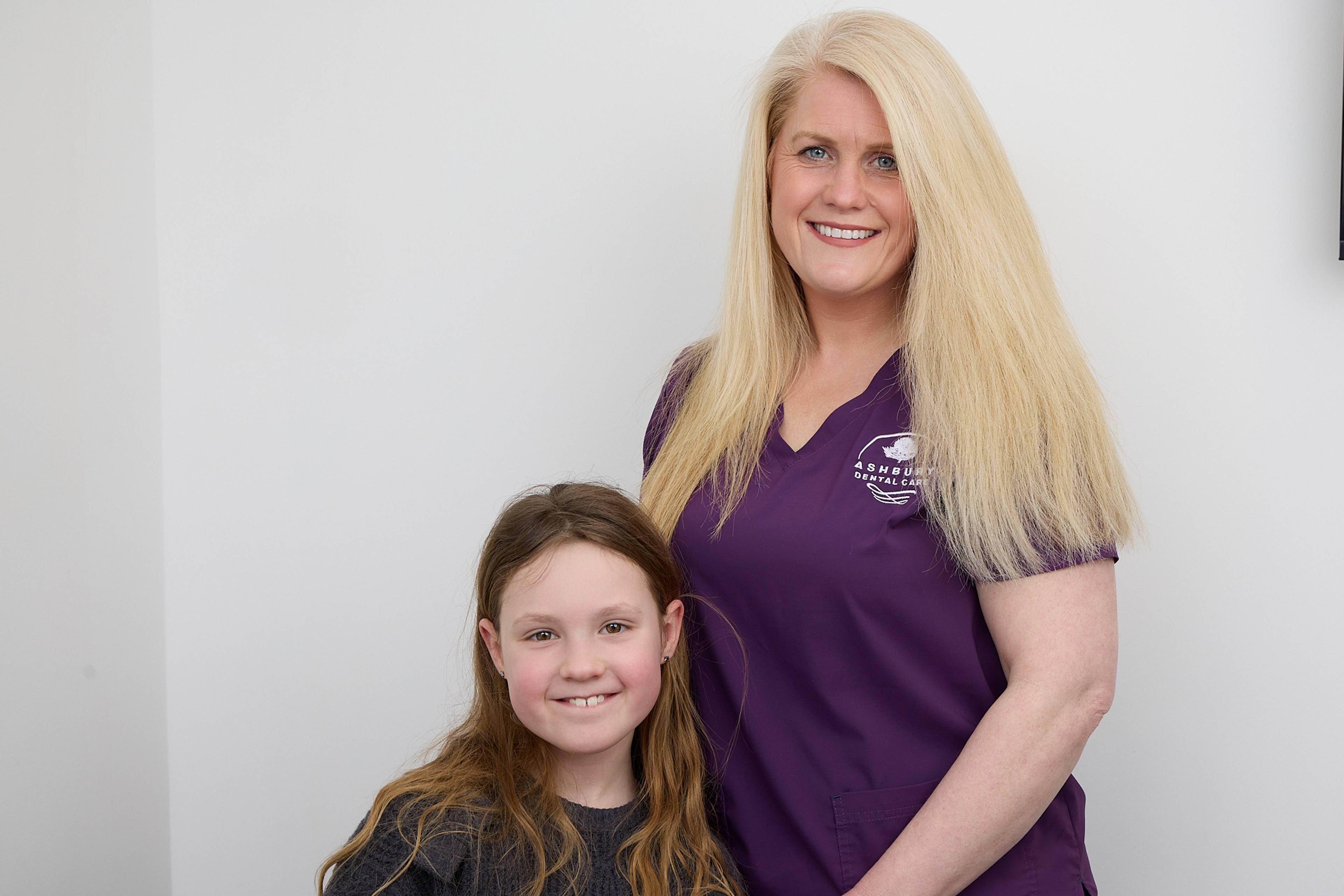 Smiling hygienist and child standing for photo