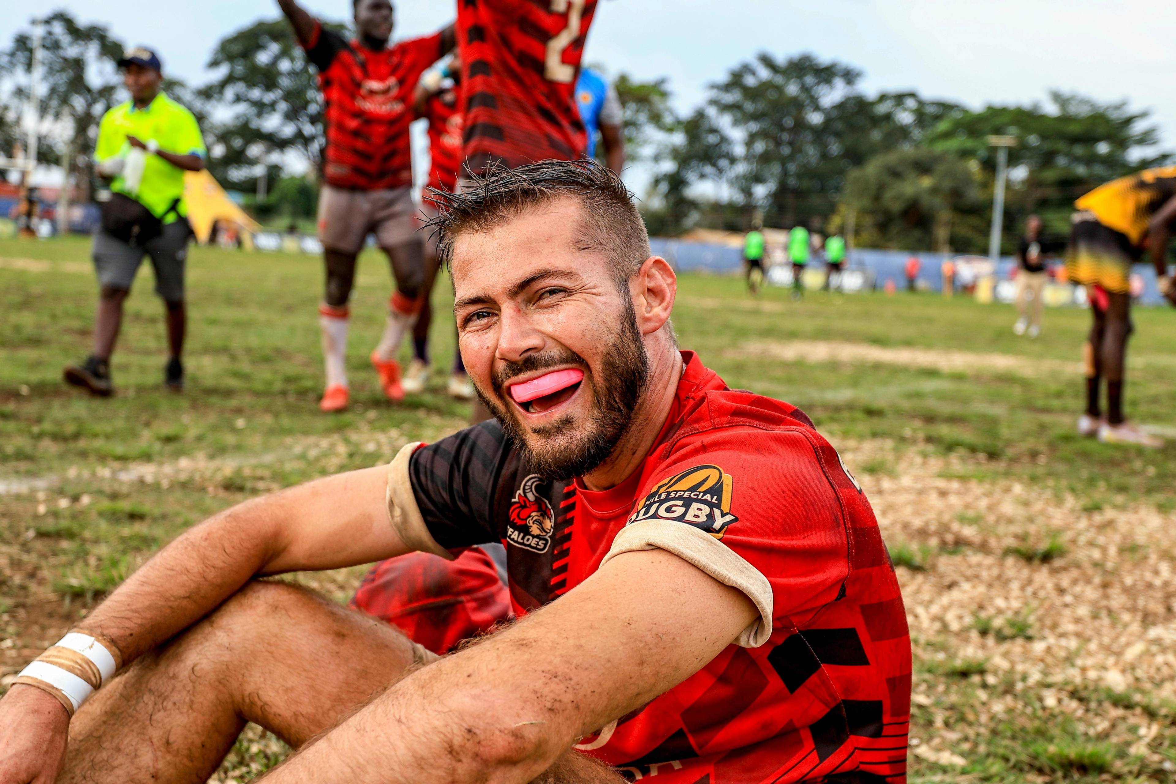 A smiling man in a red tshirt wearing a pink gum shield