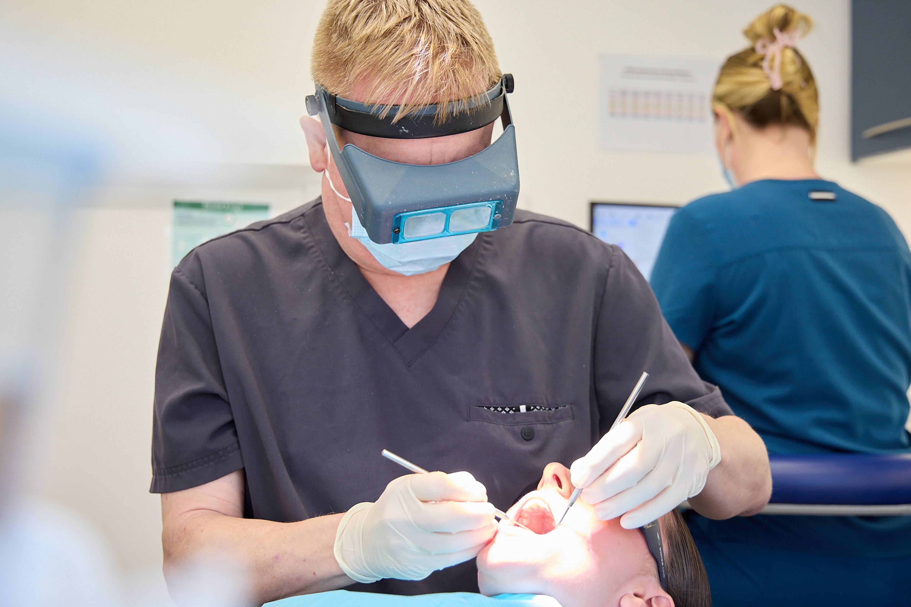 Dentist at Ashbury Dental Care working on patient using some dental tools