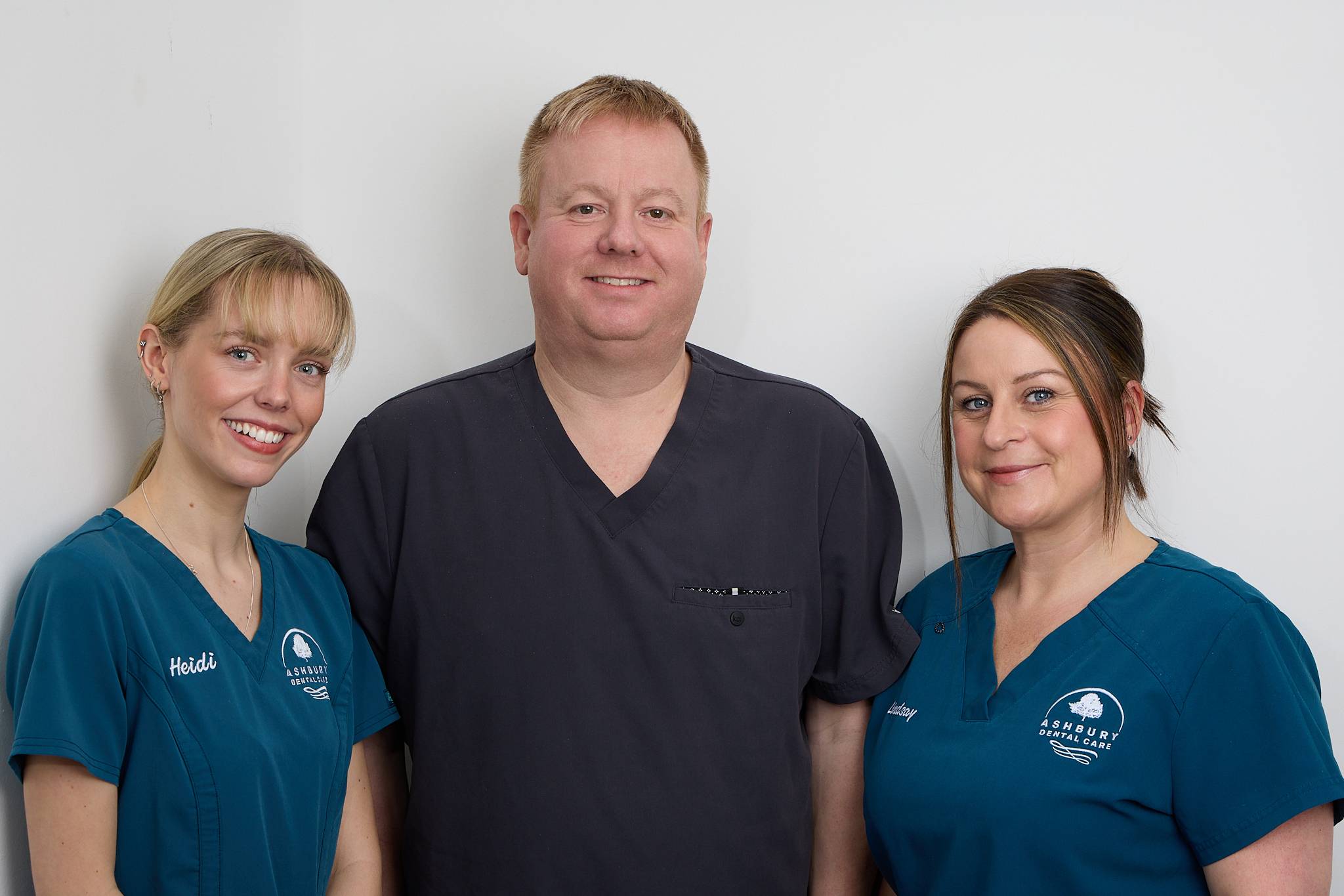 dental nurses in blue uniform smiling with dentist in grey uniform