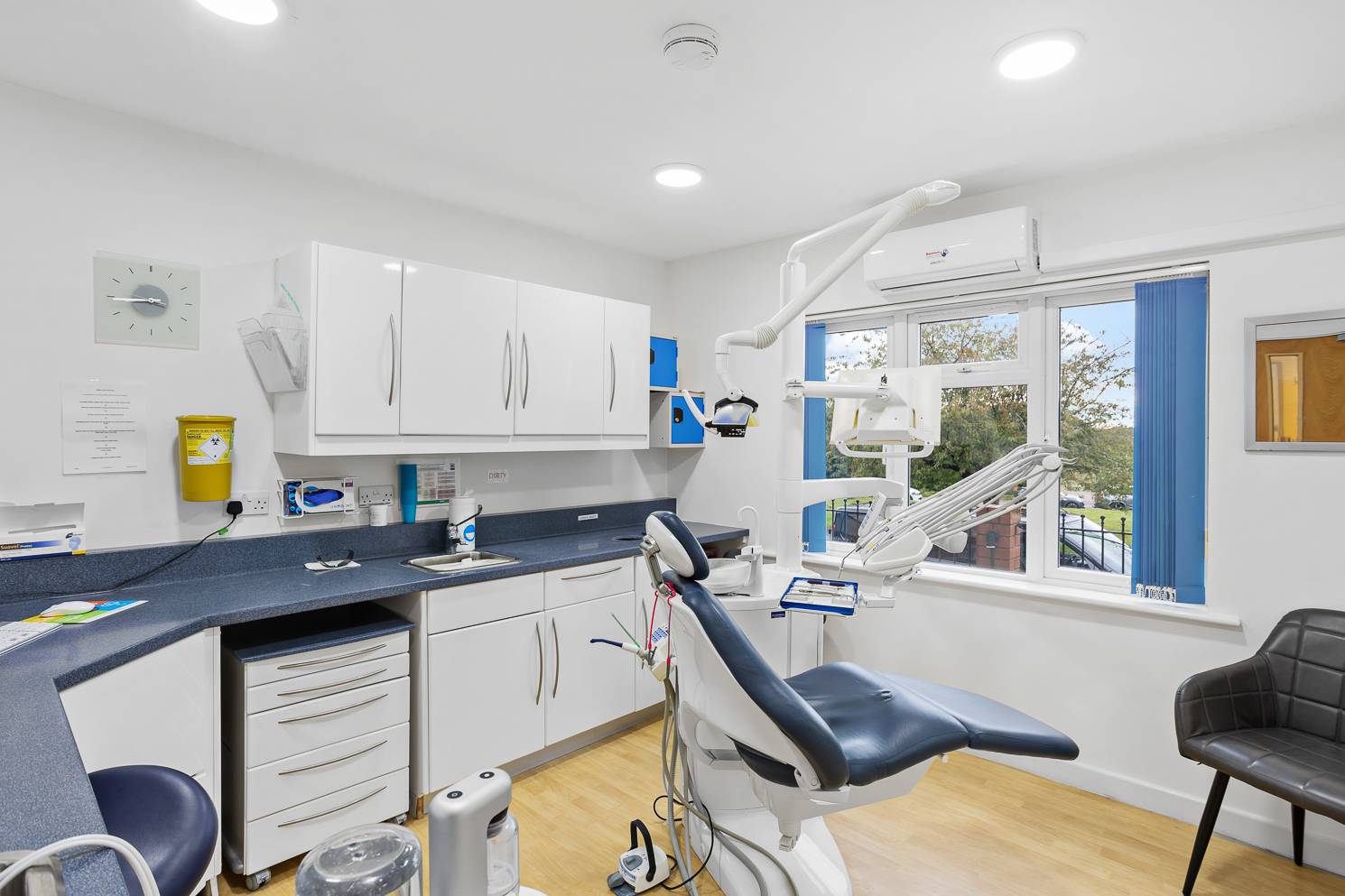 A bright, well-lit, and clean treatment room in Ashbury Dental Care's practice, with a leafy view from the window.