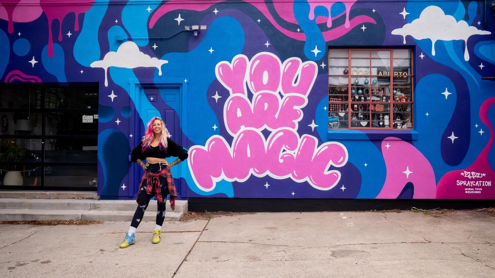 Zuzu standing in front of the You Are Magic SPRAYCATION mural