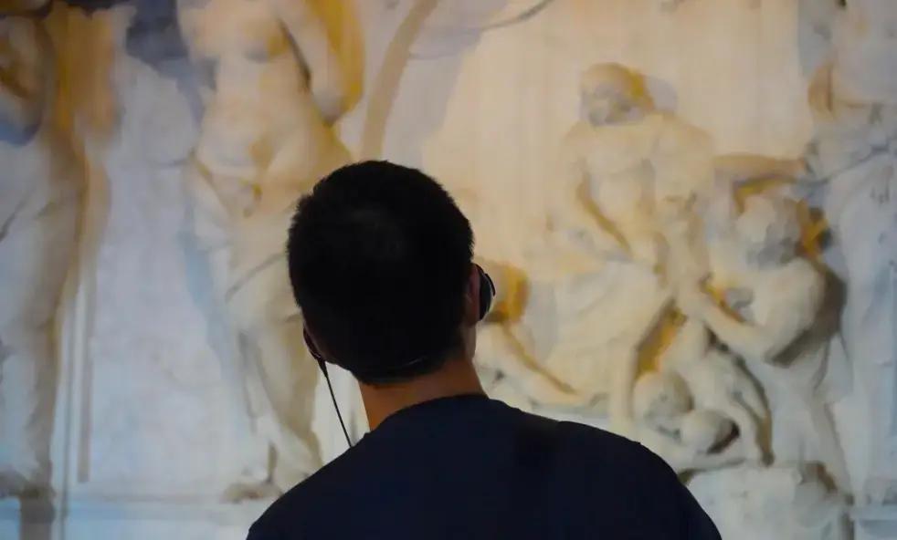 Person, der observerer indviklet marmorreliéfskulptur i museum eller galleri