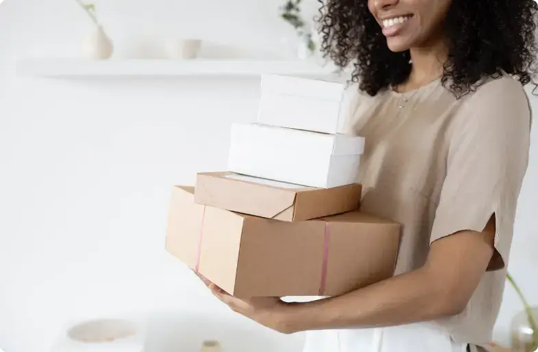 Persona sorridente che tiene una pila di scatole di spedizione marroni e bianche