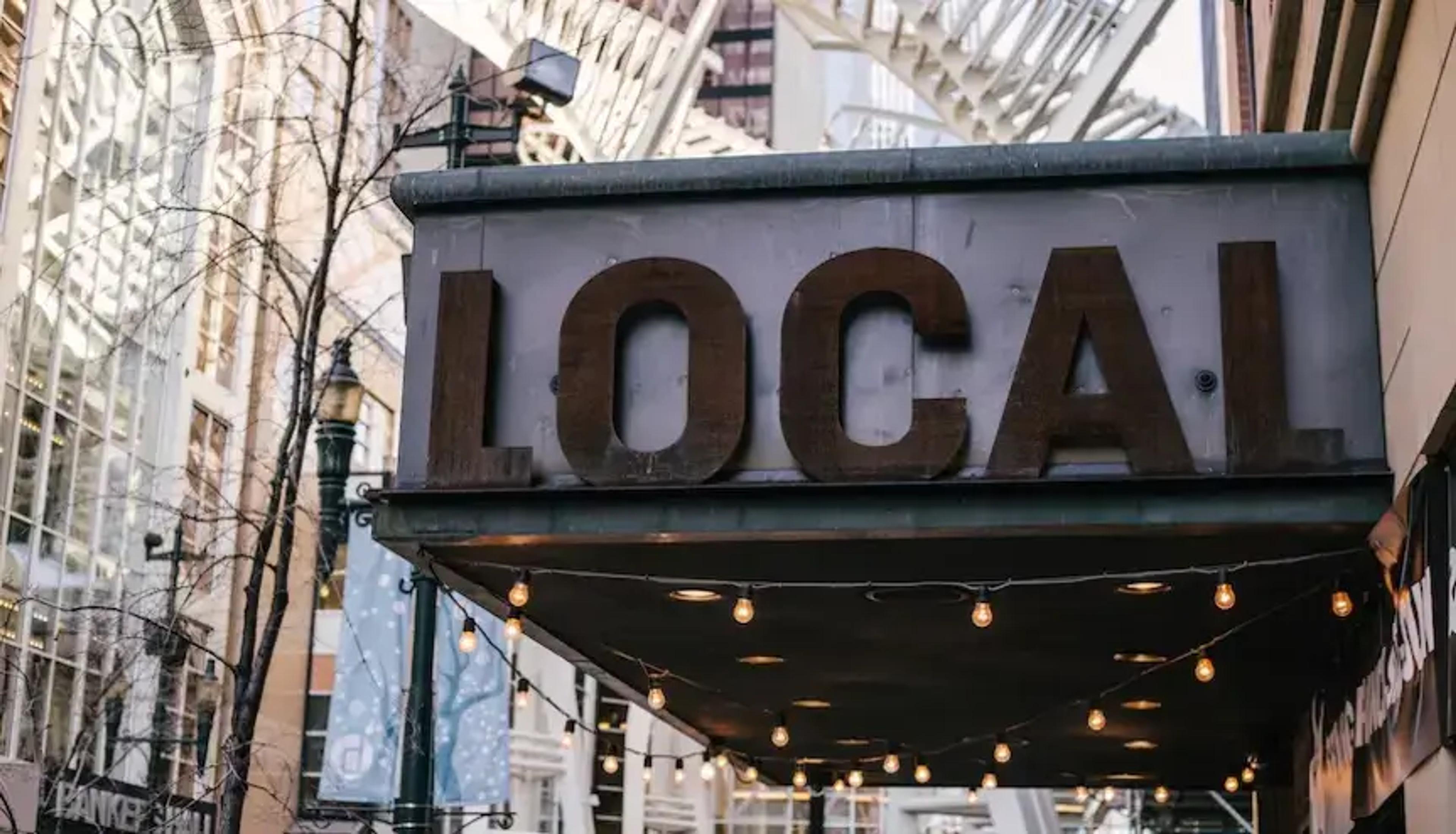 城市建筑上悬挂灯泡的“LOCAL”霓虹灯招牌