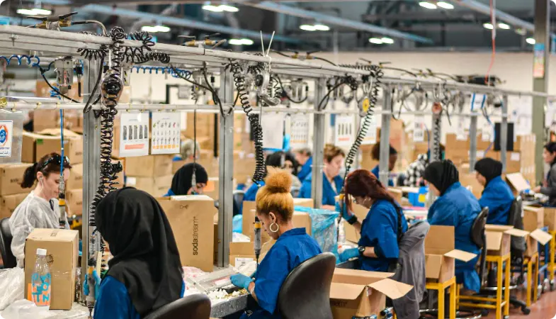 Arbeiter, die Kisten an einer Produktionslinie mit über Kopf Unterstützungsausrüstung verpacken