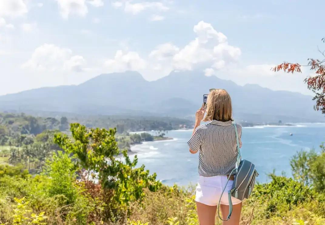Toerist die uitkijkt over een schilderachtig kustlandschap met bergen en tropische vegetatie
