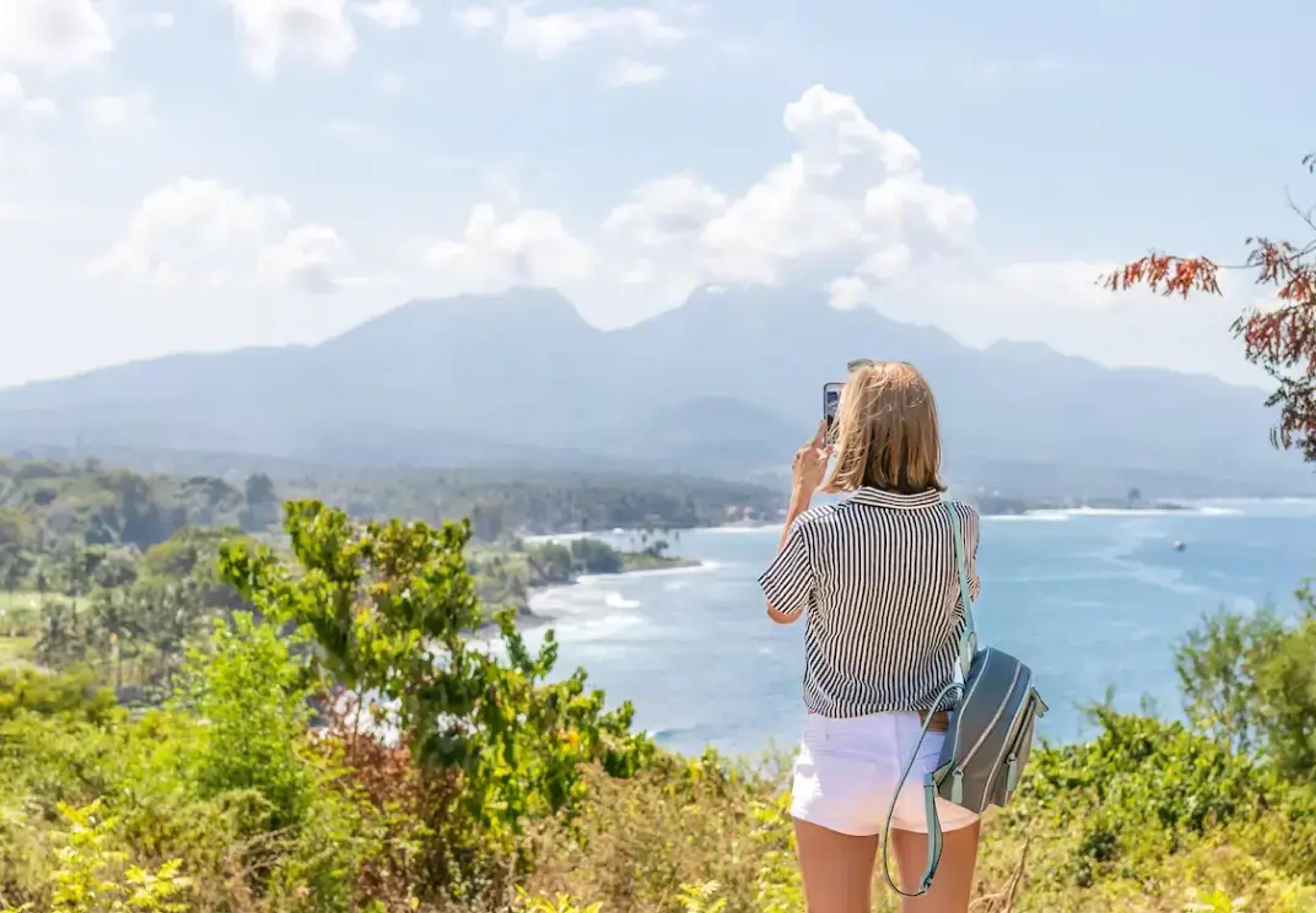 Touriste surplombant un paysage côtier pittoresque avec des montagnes et une végétation tropicale