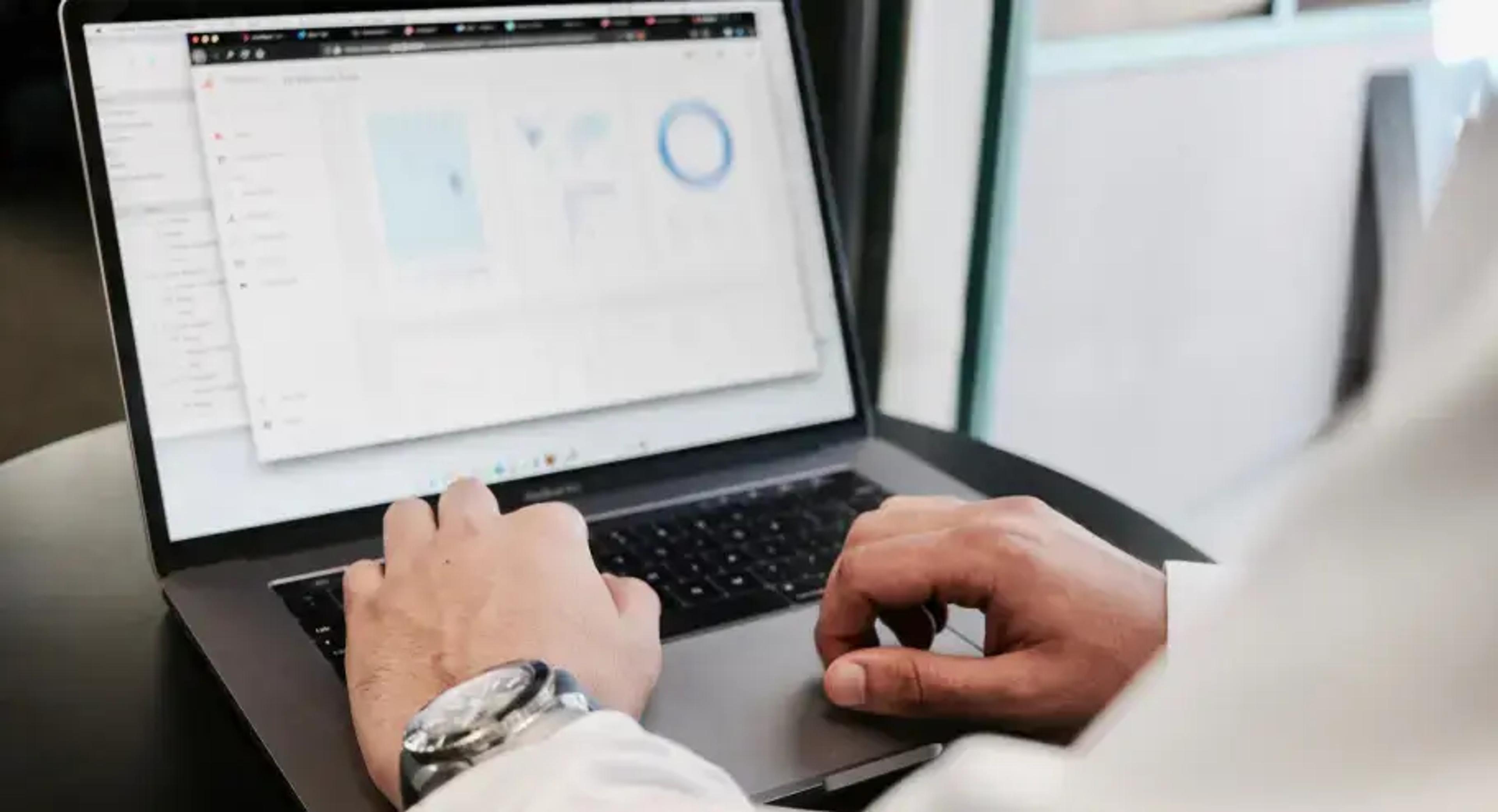 Pessoa trabalhando em um laptop com painel de análise de dados na tela