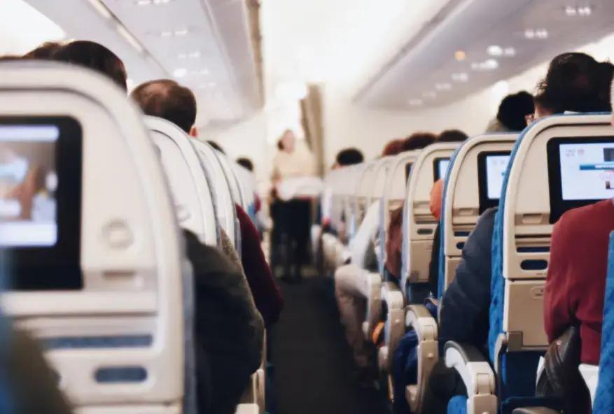 Interieur van een vliegtuigcabine met passagiers en in-flight entertainment schermen