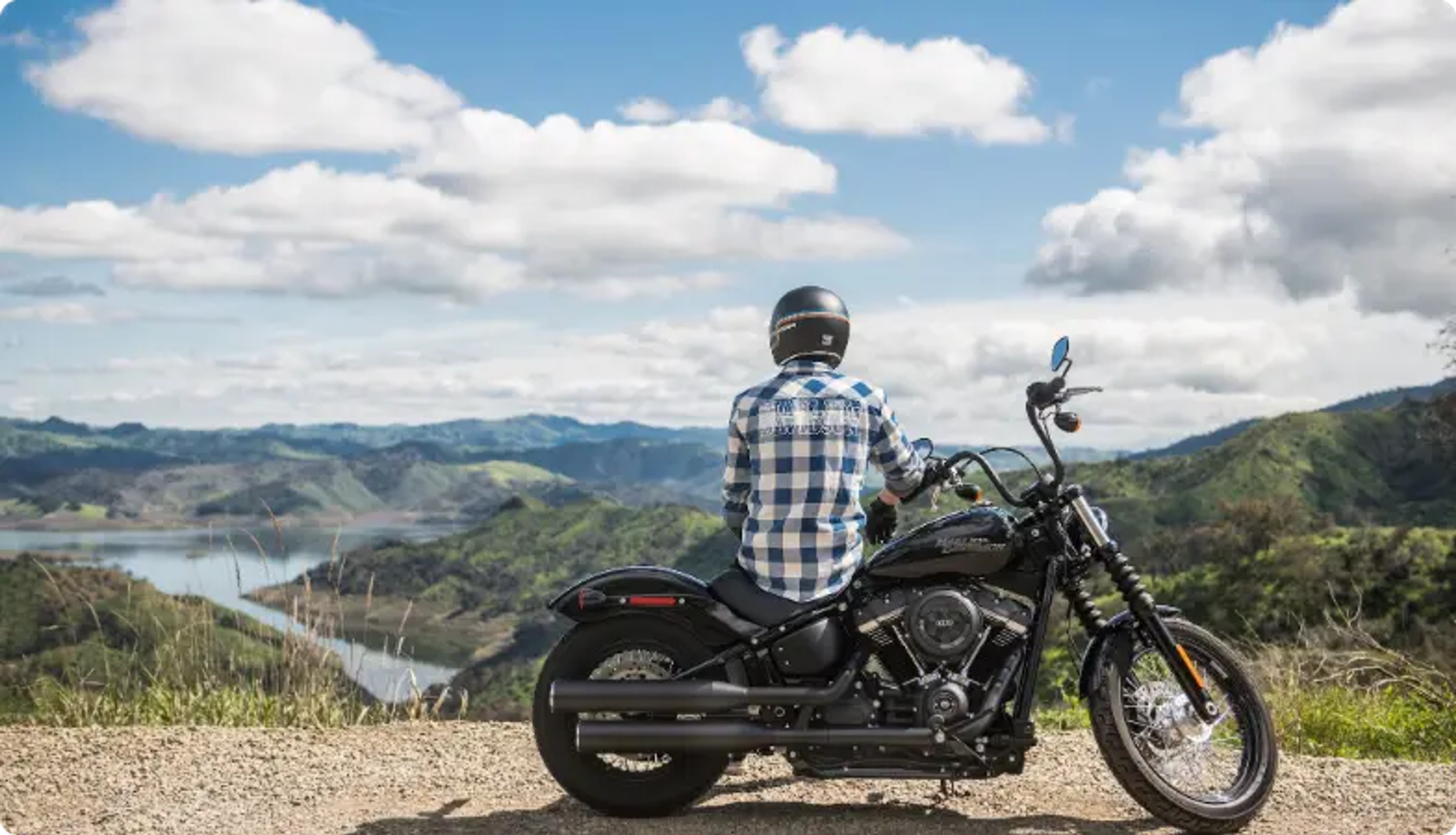 Motard sur une moto noire surplombant un paysage de montagne et de lac pittoresque