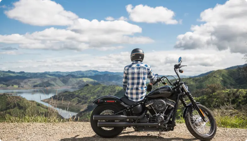 Motoros fekete motoron, festői hegyi és tó tájat nézve