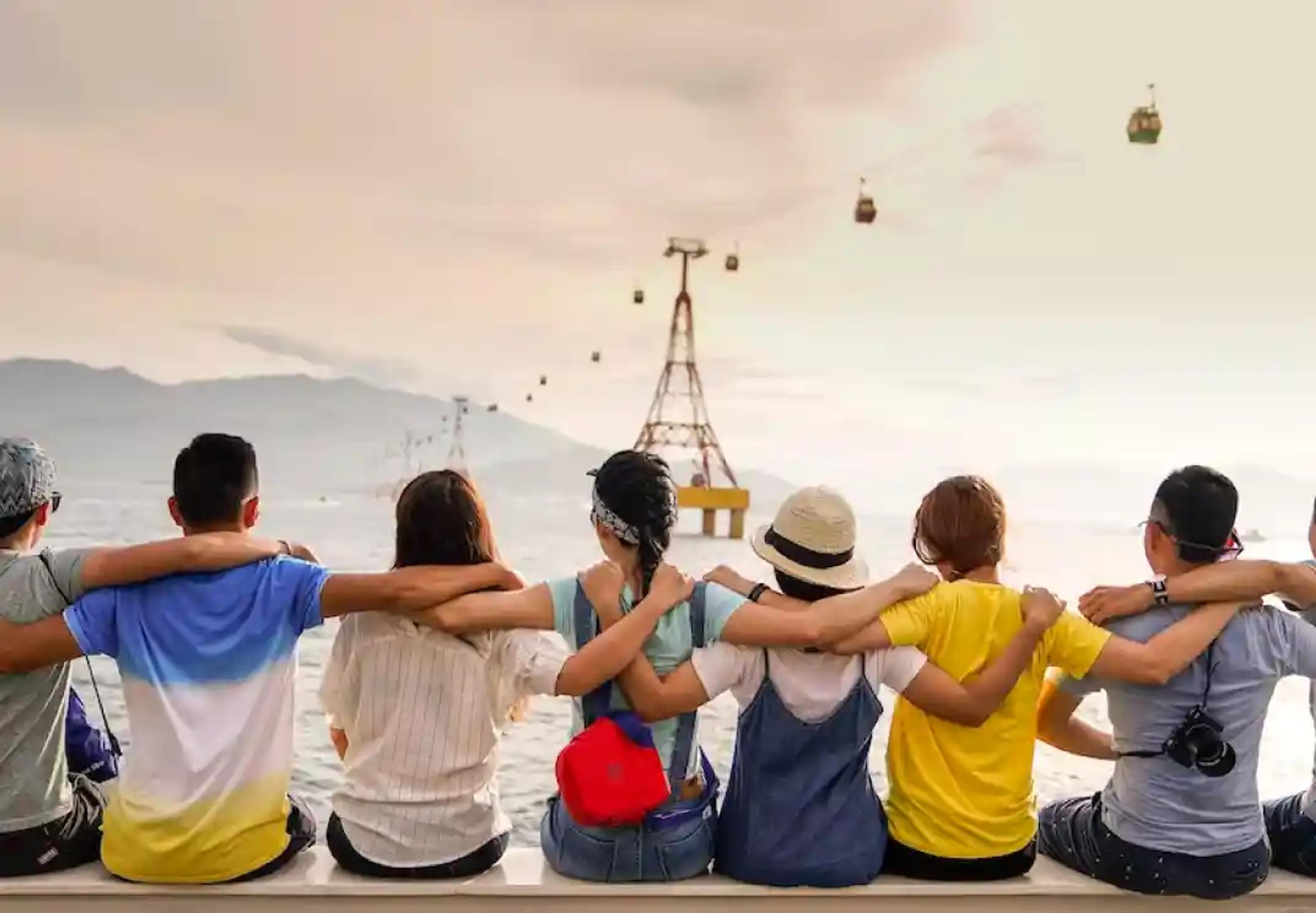 Grupo de amigos sentados juntos, a olhar para os teleféricos e as montanhas
